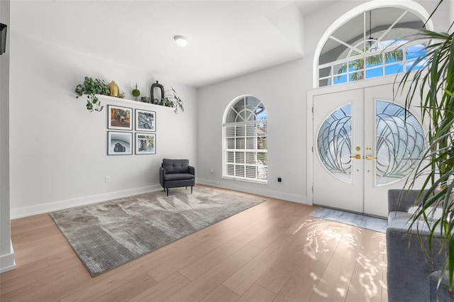 foyer with french doors, high vaulted ceiling, and light hardwood / wood-style floors