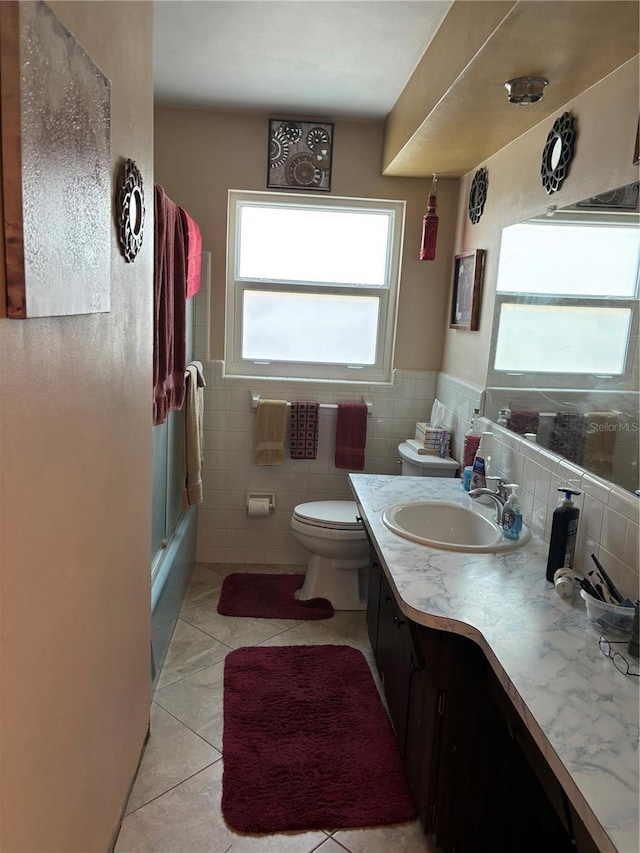 full bathroom featuring bath / shower combo with glass door, tile walls, vanity, toilet, and tile patterned floors