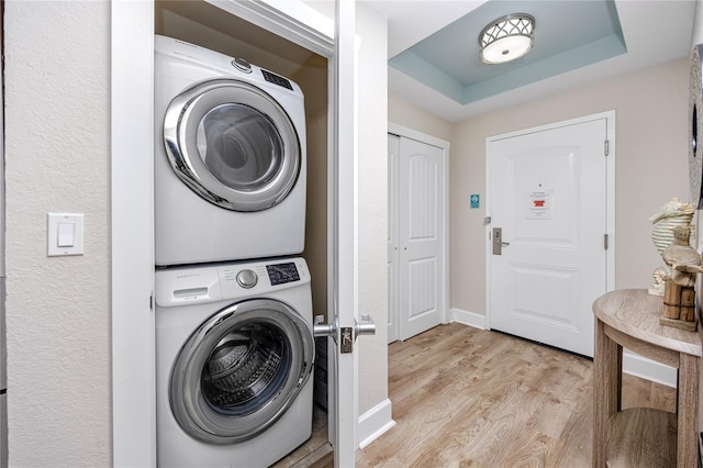 clothes washing area with light hardwood / wood-style floors and stacked washing maching and dryer