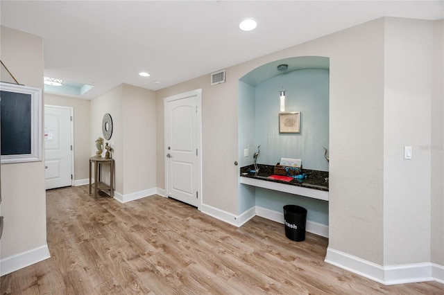 foyer entrance featuring light wood-type flooring and built in desk