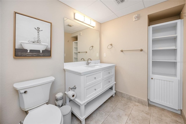 bathroom with tile patterned flooring, vanity, a drop ceiling, and toilet