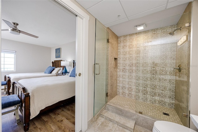 bathroom featuring a shower with door, toilet, ceiling fan, and hardwood / wood-style flooring