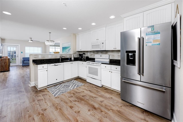 kitchen with white appliances, white cabinets, hanging light fixtures, light wood-type flooring, and kitchen peninsula