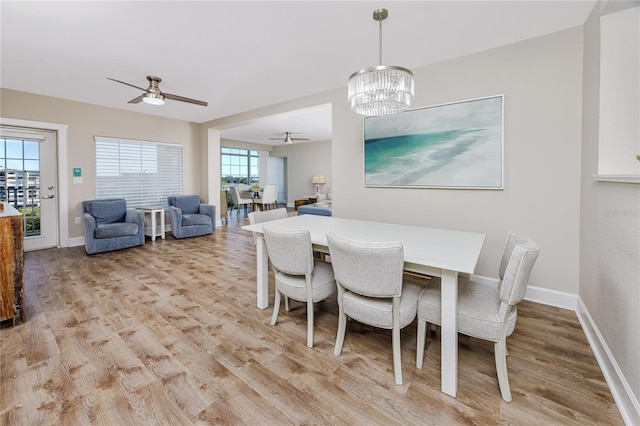 dining space featuring ceiling fan with notable chandelier, light hardwood / wood-style floors, and a healthy amount of sunlight