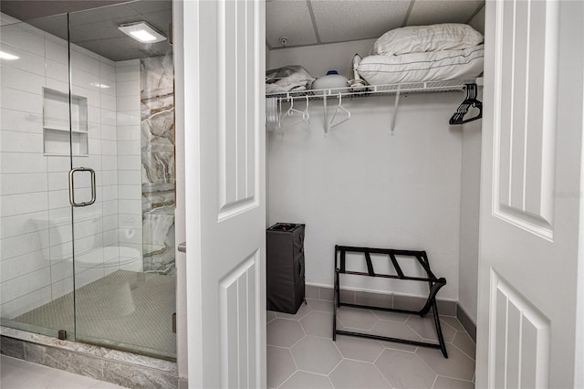 bathroom featuring tile patterned floors, a drop ceiling, and a shower with door