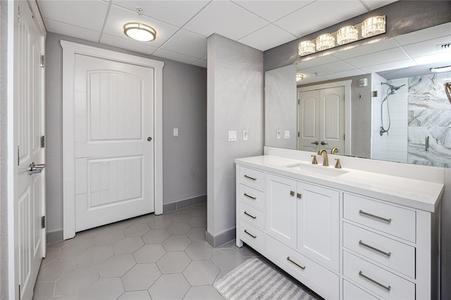 bathroom with a shower, tile patterned flooring, vanity, and a drop ceiling