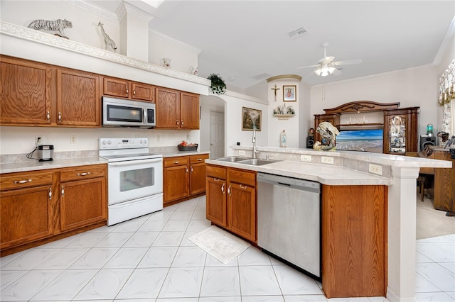 kitchen with a center island with sink, sink, ceiling fan, ornamental molding, and stainless steel appliances