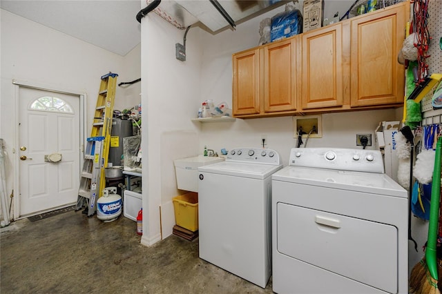 clothes washing area with cabinets, sink, and washing machine and clothes dryer