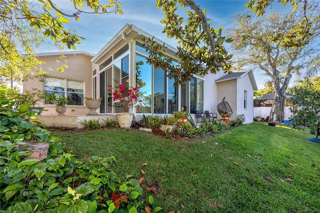 back of property featuring a lawn and a sunroom