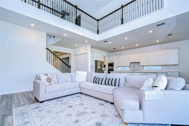 living room featuring light hardwood / wood-style floors, sink, and a high ceiling