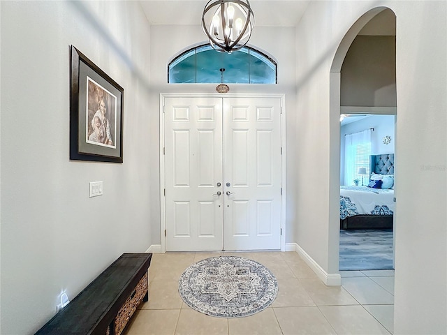 foyer with light tile patterned floors, an inviting chandelier, and a high ceiling