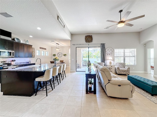 living room featuring light tile patterned floors, a textured ceiling, a wealth of natural light, and ceiling fan