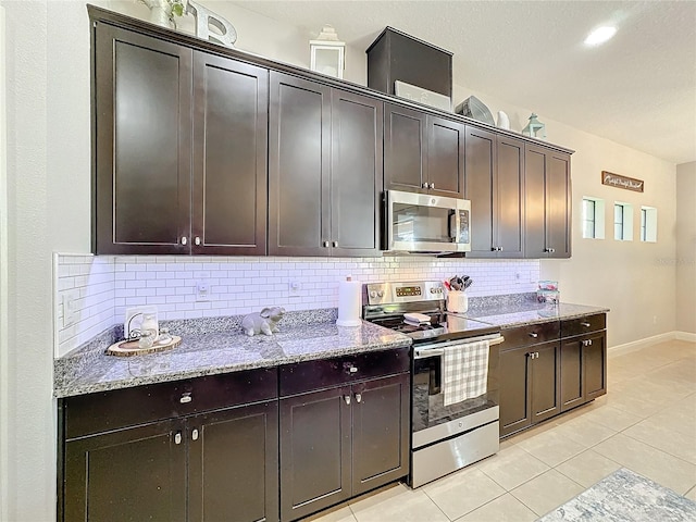 kitchen featuring decorative backsplash, light tile patterned floors, dark brown cabinetry, and stainless steel appliances