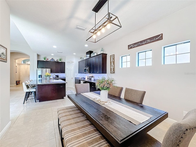 tiled dining room featuring a notable chandelier and sink