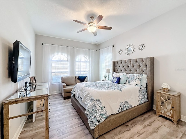 bedroom featuring ceiling fan, light hardwood / wood-style floors, and multiple windows