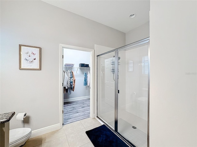 bathroom featuring toilet, tile patterned floors, and walk in shower