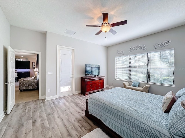 bedroom with ceiling fan, a textured ceiling, and light wood-type flooring