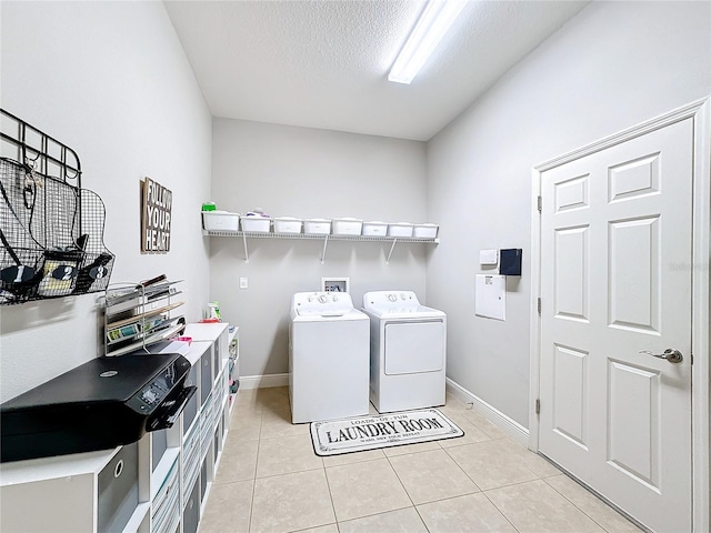 washroom featuring washing machine and clothes dryer, light tile patterned floors, and a textured ceiling