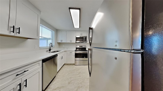 kitchen with white cabinetry, sink, stainless steel appliances, and light stone counters