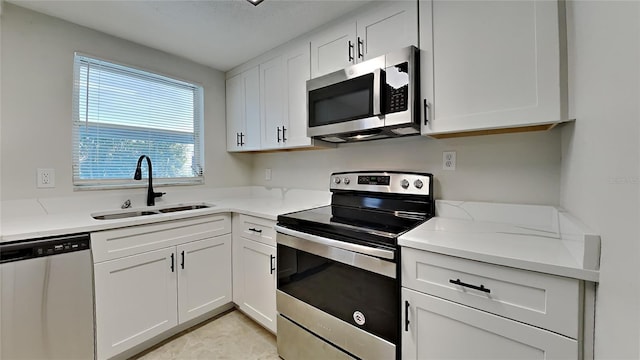 kitchen with light stone countertops, white cabinetry, sink, and appliances with stainless steel finishes