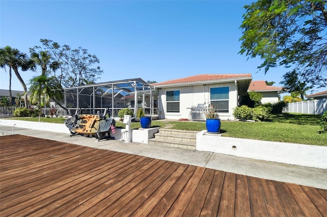 rear view of property featuring glass enclosure and a yard