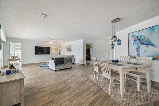 dining room with ceiling fan, a textured ceiling, and light wood-type flooring