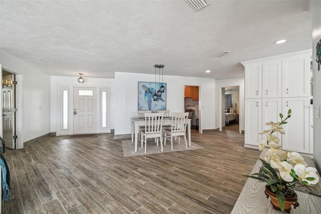 unfurnished dining area featuring a textured ceiling and dark hardwood / wood-style flooring