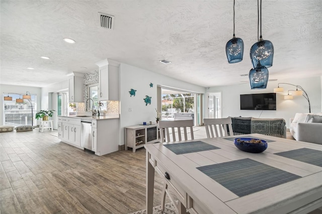 dining space featuring a textured ceiling, light hardwood / wood-style flooring, and sink