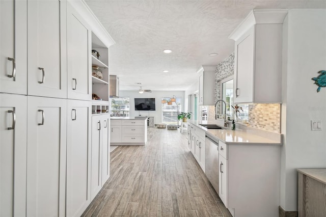 kitchen with sink, light hardwood / wood-style flooring, stainless steel dishwasher, white cabinetry, and kitchen peninsula