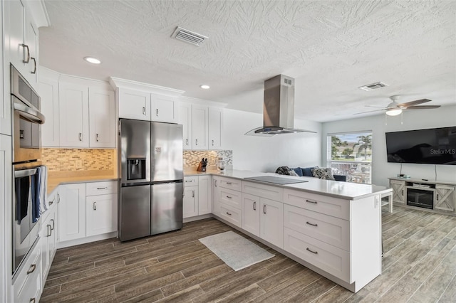 kitchen featuring kitchen peninsula, appliances with stainless steel finishes, dark hardwood / wood-style flooring, extractor fan, and white cabinets