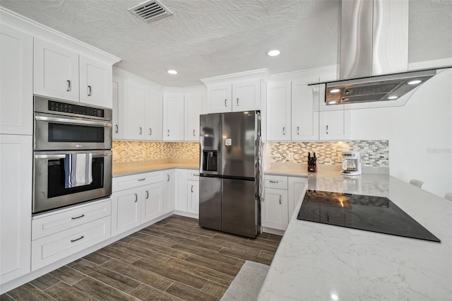 kitchen with white cabinets, dark hardwood / wood-style floors, island exhaust hood, and appliances with stainless steel finishes