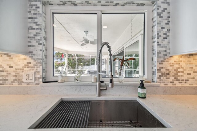 details with light stone counters, sink, and tasteful backsplash