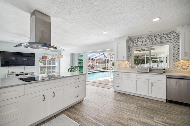 kitchen featuring white cabinets, stainless steel dishwasher, wall chimney exhaust hood, black electric cooktop, and tasteful backsplash