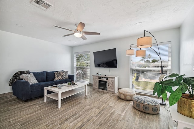 living room with a textured ceiling, hardwood / wood-style flooring, and ceiling fan