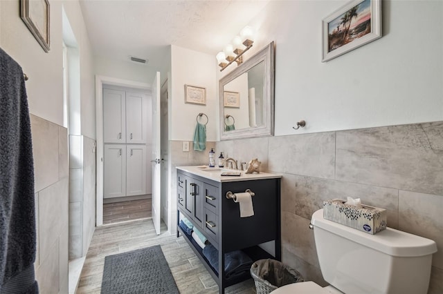 bathroom with wood-type flooring, vanity, and tile walls