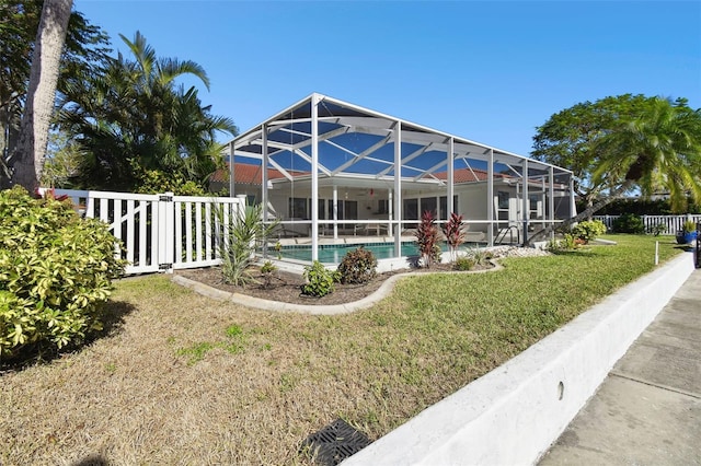 view of pool featuring glass enclosure and a yard