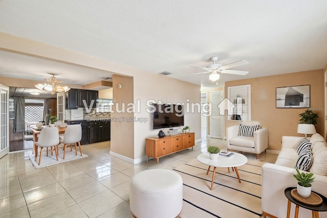 tiled living room featuring a textured ceiling and ceiling fan with notable chandelier