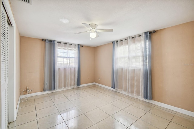 tiled spare room with ceiling fan