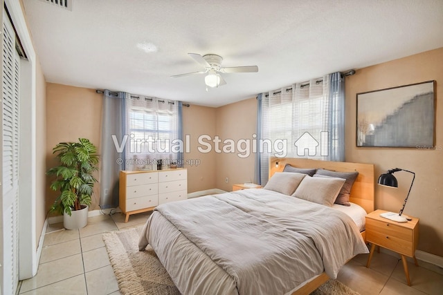 bedroom with ceiling fan, light tile patterned flooring, and a textured ceiling