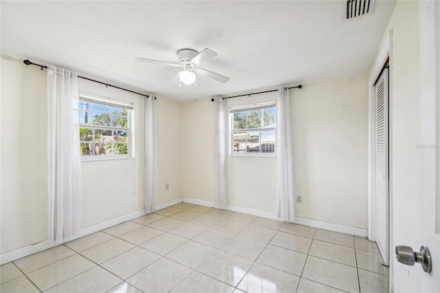 tiled spare room featuring a wealth of natural light and ceiling fan