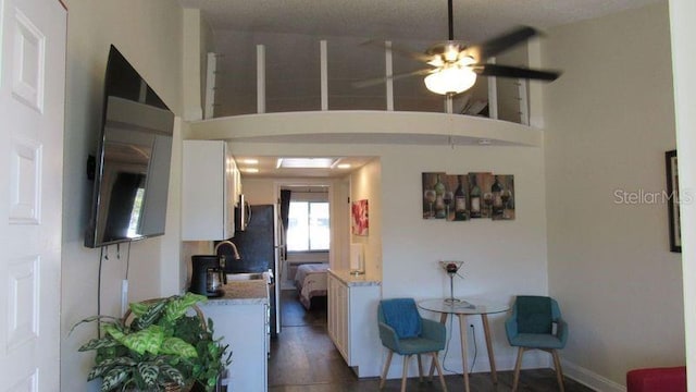 living room featuring a textured ceiling, ceiling fan, dark wood-type flooring, and sink