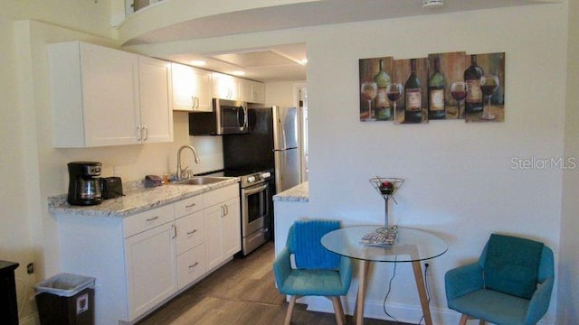20853 Haulover Cv Unit A8, Lutz, FL 33558 - kitchen with a sink, stainless steel appliances, white cabinets, wood finished floors, and light stone countertops