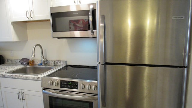 kitchen featuring light stone countertops, white cabinetry, sink, and appliances with stainless steel finishes