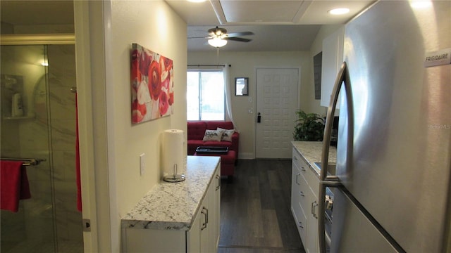 kitchen featuring white cabinetry, stainless steel fridge, dark wood-type flooring, and light stone counters