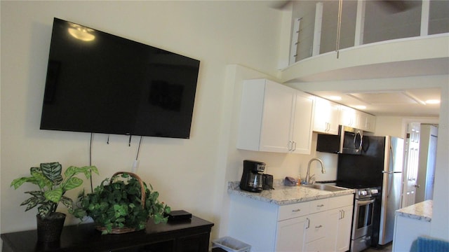 kitchen with white cabinetry, sink, light stone counters, and appliances with stainless steel finishes