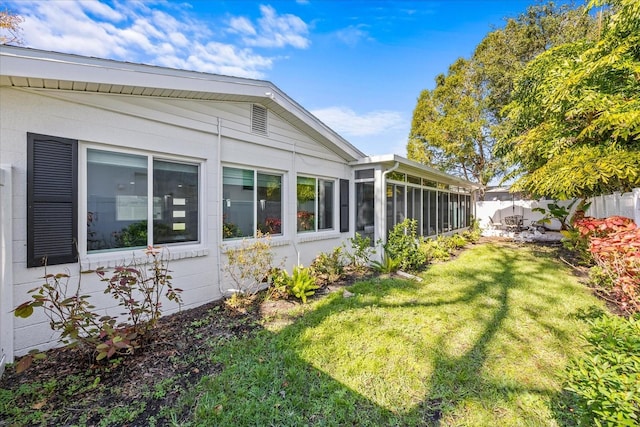 view of side of home with a lawn and a sunroom