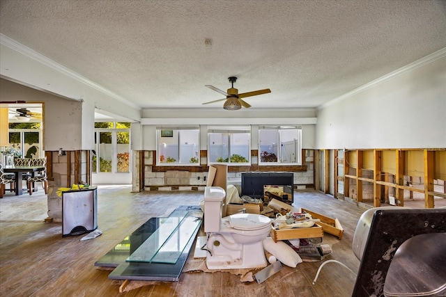 living room featuring a textured ceiling, hardwood / wood-style flooring, ceiling fan, and crown molding