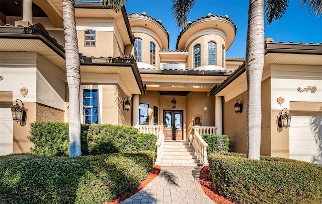 doorway to property featuring french doors, covered porch, and a garage