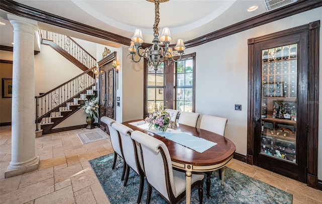 dining space with a raised ceiling, decorative columns, an inviting chandelier, and ornamental molding