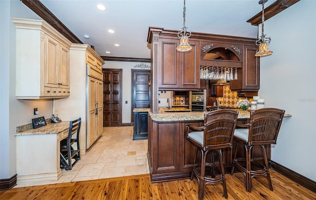 kitchen featuring light stone counters, light hardwood / wood-style flooring, pendant lighting, and ornamental molding